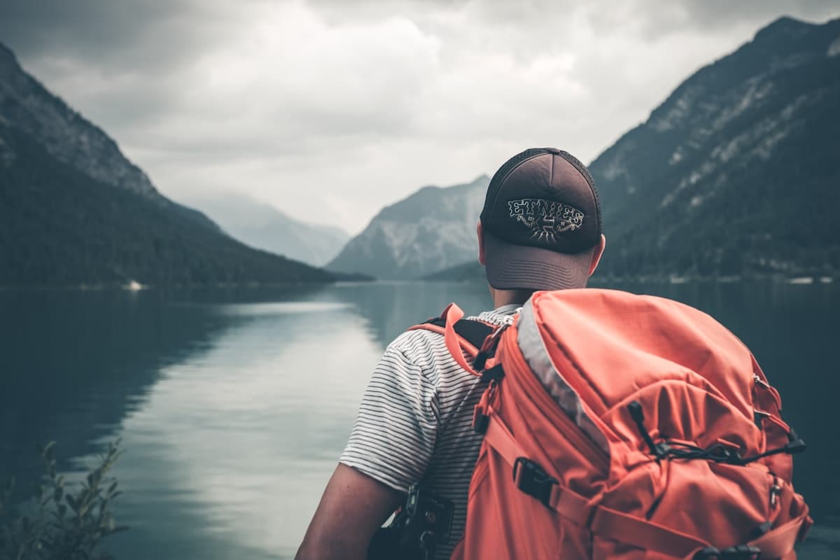 Reisender mit Rucksack blickt über einen See in den Bergen — Symbol für die generierte Route
